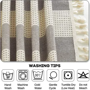 Détail de la nappe rayée en lin et coton avec pompons et icônes d'entretien du lavage.