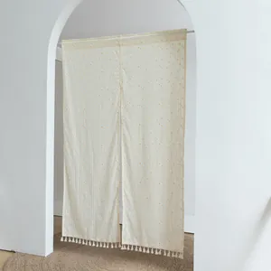 Close-up of off-white polka dot fabric door curtain with delicate tassel fringe detailing.