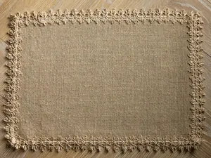 Rectangle natural burlap placemat featuring decorative lace border on wood table.