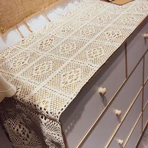Detail of a vintage hollow lace crochet table runner on a wooden dresser cabinet, retro style