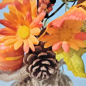 Harvest festival decor with artificial pumpkin, berries, and maple leaves in burlap wrap