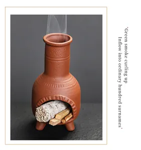 Traditional handmade purple clay chimenea incense burner with smoldering sage bundle