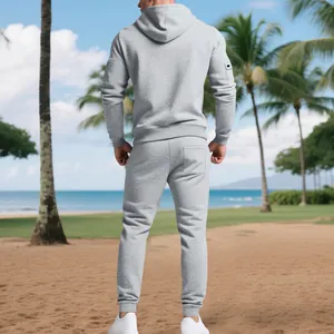 Back view of a man wearing a grey heavyweight fleece hoodie and jogger set on a beach