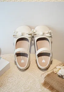Gros plan de chaussures Mary Jane blanches pour filles avec nœud en perles élégant