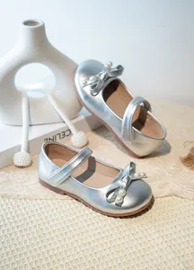 Gros plan sur d'élégantes chaussures Mary Jane argentées pour filles avec noeud en perles