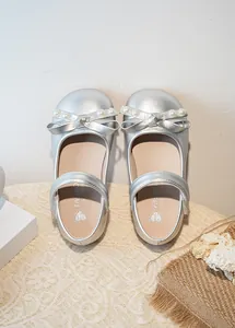 Vue de dessus de chaussures de princesse argentées avec nœuds ornés de perles.
