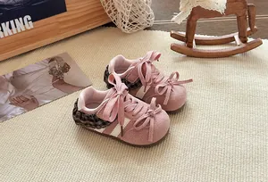 Detail van roze peutersneakers met strikjes en geruite bies in een sfeervolle setting