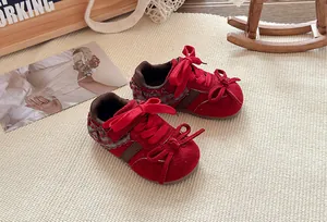 Detailopname van rode kindersneakers met delicate kanten randen en een stijlvolle strik