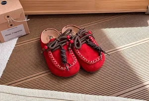 Detail van retro rode suède klompen voor meisjes met kralen en touw decoraties