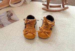 Detailopname van gele kindersneakers met strikjes en panterprint op de hiel.