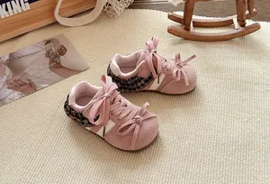 Detailweergave van roze meisjessneakers met ruitjes en schattige strikjes.
