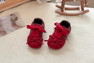 Gedetailleerd overzicht van rode suède sneakers voor meisjes met een schattig dubbel strikje