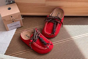 Gedetailleerd overzicht van rode suède kinderslippers met kralenkoorden en stiksel