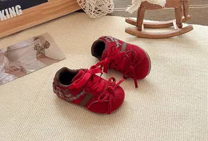 Gedetailleerde weergave van rode meisjessneakers met strikken op een geweven beige mat