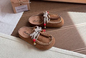 Detailweergave van vintage bruine suède klompen voor meisjes met decoratieve kralenveters.