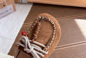 Detailopname van bruine suède meisjesslippers met kralen en stikseldetails