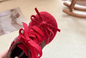 Detailopname van een rode kindersneaker met een decoratieve strik en vetersluiting