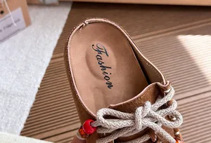 Close-up van vintage bruine suède klompen voor meisjes met gekleurde kralen en veters