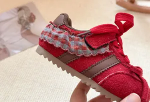 Detailopname van rode peutersneakers met geruite ruches en bruine strepen op de zijkant