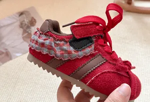 Detailopname van rode kindersneakers met ruitjesstrik en dikke zool voor meisjes.