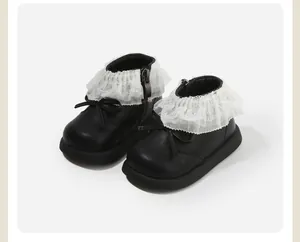 Detail view of toddler girl black leather boots with elegant white lace ruffles and bow decoration.
