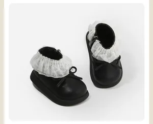 Detail of black toddler leather boots with white lace collar and cute bow.