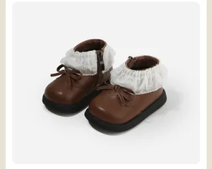 Close-up of brown toddler girl's boots featuring delicate lace ruffles and bow accents