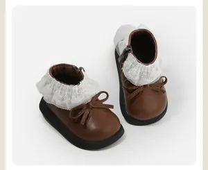 Close-up of brown toddler girl boots with white lace collar and decorative bow