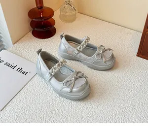 Detail view of silver girl's princess shoes with pearl straps and decorative bows.