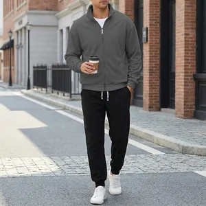 Tuta sportiva casual da uomo grigia con giacca a zip e pantaloni sportivi neri da esterno.