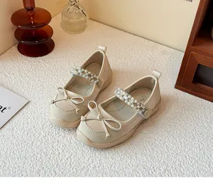 Elegant beige girls' Mary Jane shoes with rhinestone straps and delicate bow details.