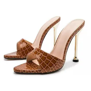 Detailed view of the brown crocodile skin texture on pointed-toe stiletto mules
