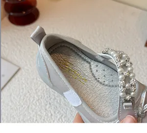 Detailed macro view of silver girl's princess shoe with elegant rhinestone pearl strap