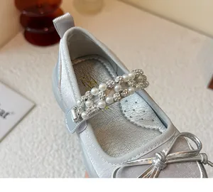 Close-up view of girl's silver princess shoe featuring pearl and rhinestone strap details.