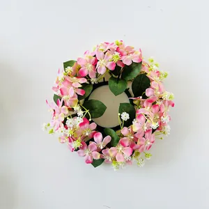 Dettaglio ghirlanda di candele con piccoli fiori di seta rosa e bianchi per decoro tavola casa