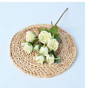 Detailed view of 8-head artificial cream roses on a woven mat for home decoration