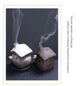 Atmospheric ceramic incense burner in small house shape with smoke curling detail.