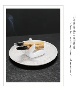 Witte keramische reliëfschaal met handvormige Palo Santo-wierookhouder detail