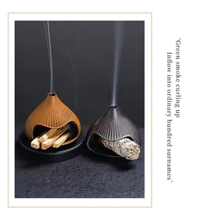Detail view of ceramic Fuji mountain incense burner with rising smoke and sage bundles
