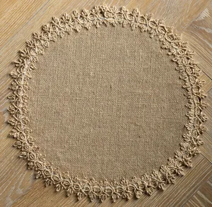 Detailed top view of a rustic round jute placemat with fringe on a wood surface