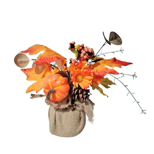 Autumn Harvest Festival decoration with artificial pumpkin, maple leaves and berries in burlap base