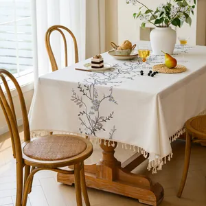 Detailed shot of the elegant embroidered floral pattern and tassel fringe on a cream tablecloth