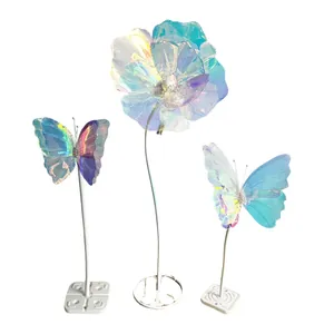 Decorazioni olografiche a forma di fiore e farfalla su alti supporti bianchi da esposizione