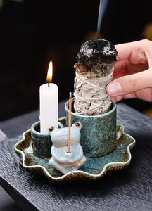 Detailed macro view of a ceramic frog incense holder set with burning sage and candle