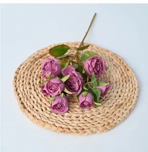 Detail view of 8-head artificial purple roses on a rustic woven straw mat