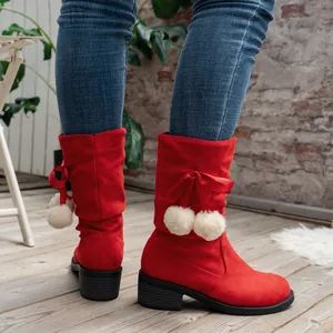 Detail showing decorative red ribbon bow and white pom-poms on red mid-calf boots