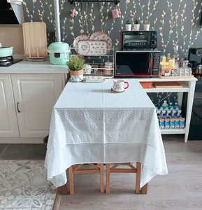 Elegant white French lace tablecloth with embroidered floral patterns in a kitchen setting.