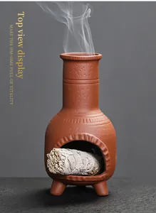Close-up view of smoke rising from a vintage terracotta sage burner with a sage bundle inside