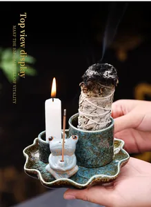 Detailed view of handmade ceramic frog incense burner with burning sage bundle and candle