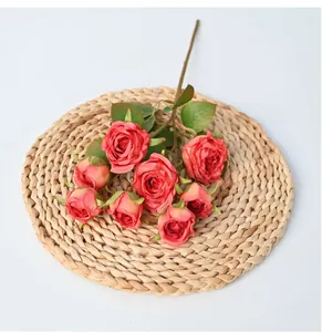 Close-up view of 8-head artificial roses with burnt edges placed on a woven straw mat